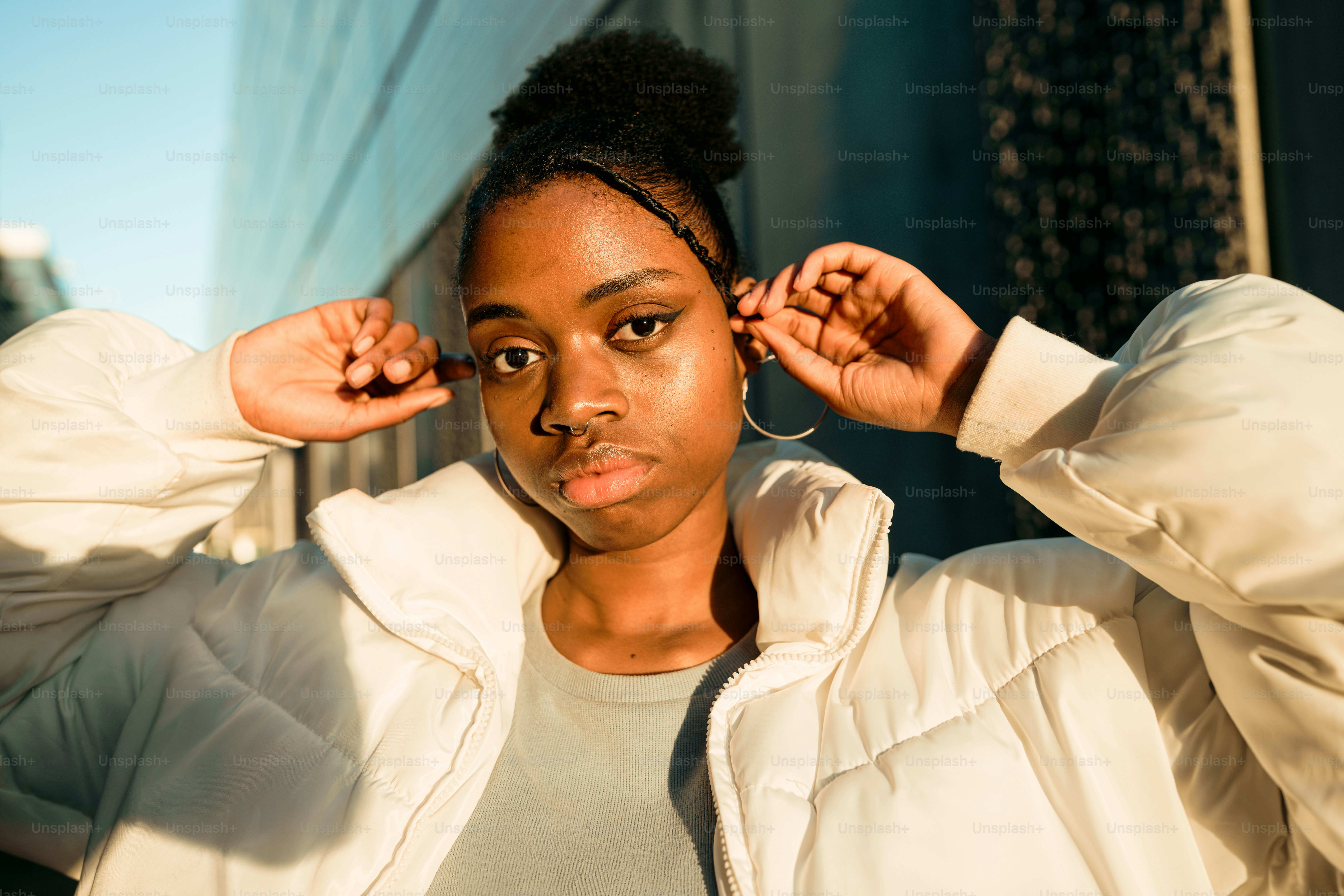 a woman in a white jacket is holding her hair