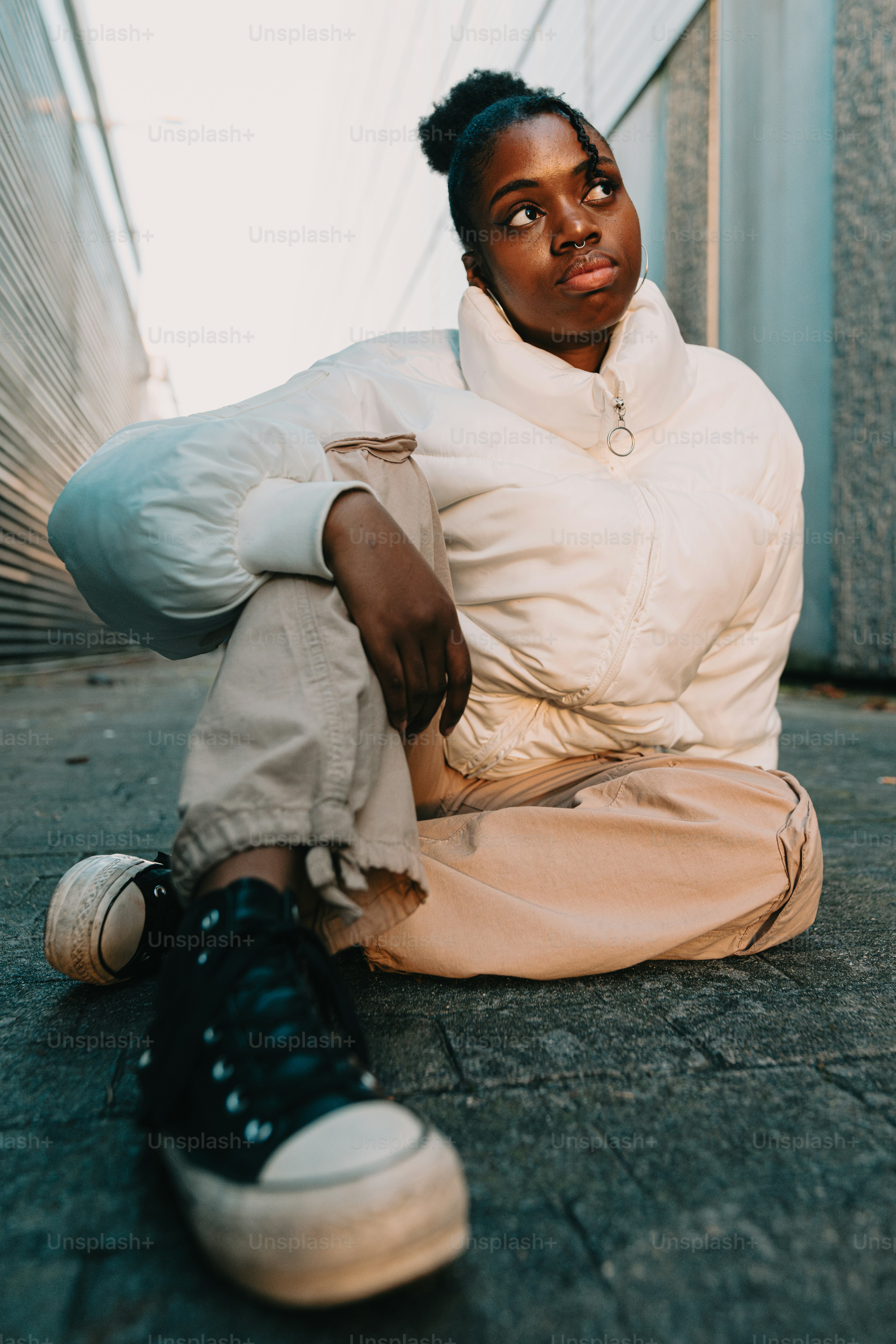A woman sitting on the ground in front of a building photo – Portrait ...