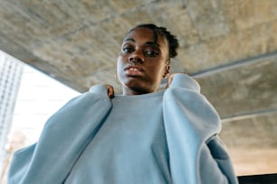 a woman in a blue sweater is standing under a bridge