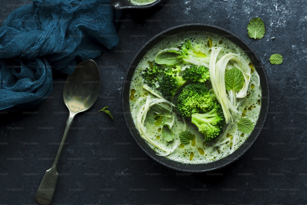 a bowl of broccoli and noodles with a spoon