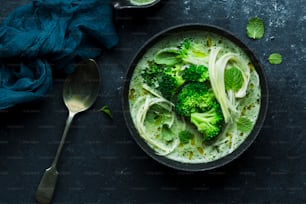 a bowl of broccoli and noodles with a spoon