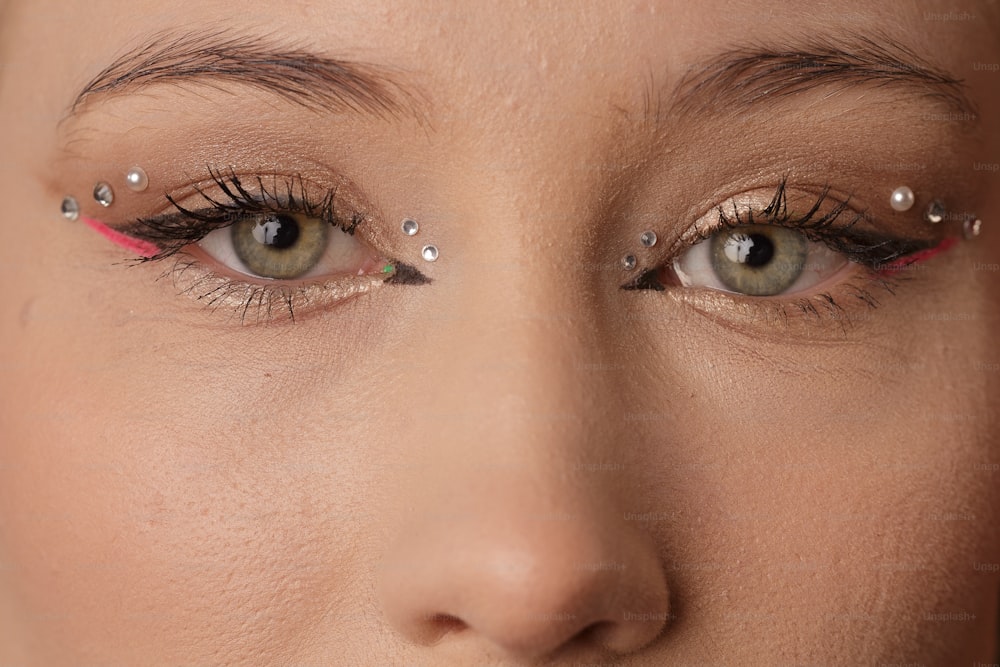 a close up of a woman's face with a pair of eyeliners
