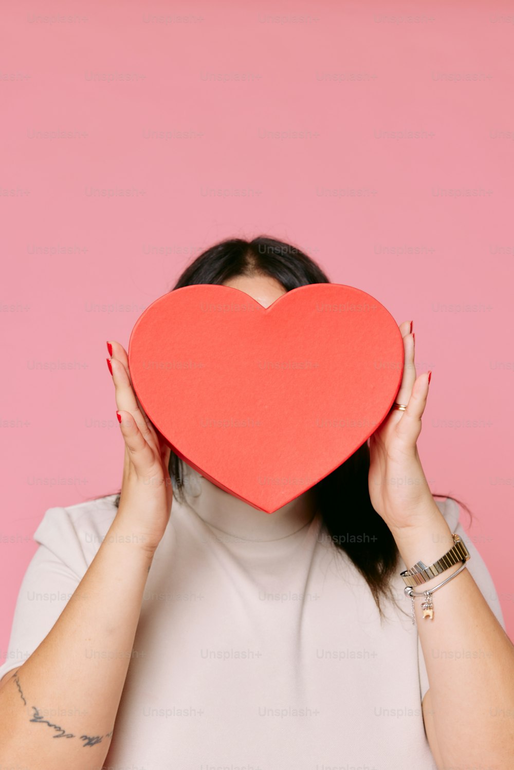 a woman covering her face with a paper heart