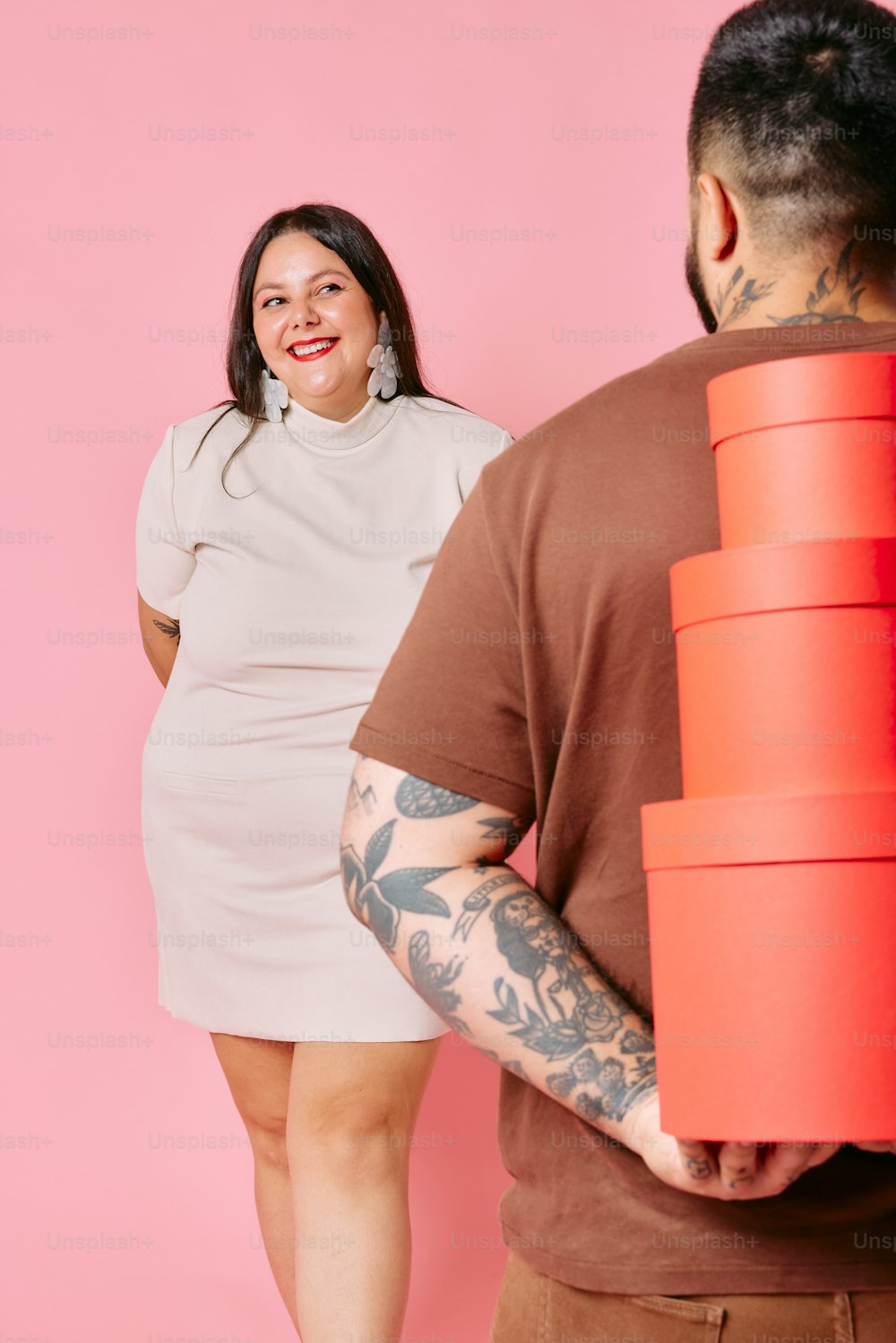 a man holding a giant stack of red cups next to a woman
