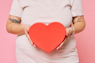 a woman holding a red heart in her hands