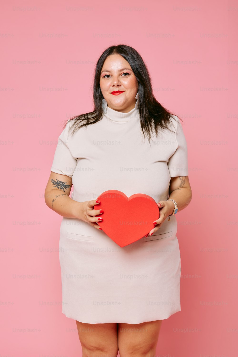 a woman in a white dress holding a red heart