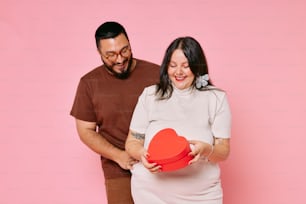 a man holding a heart shaped box next to a woman
