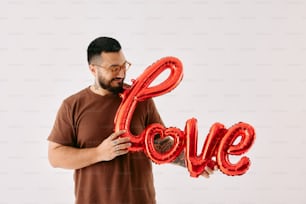 a man holding a red balloon in the shape of the word love