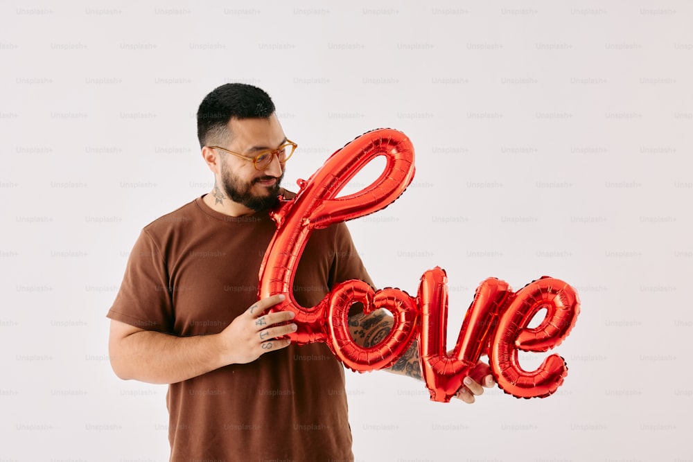 a man holding a red balloon in the shape of the word love