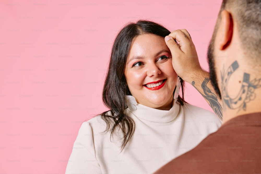 a woman is smiling as she puts on a man's hair