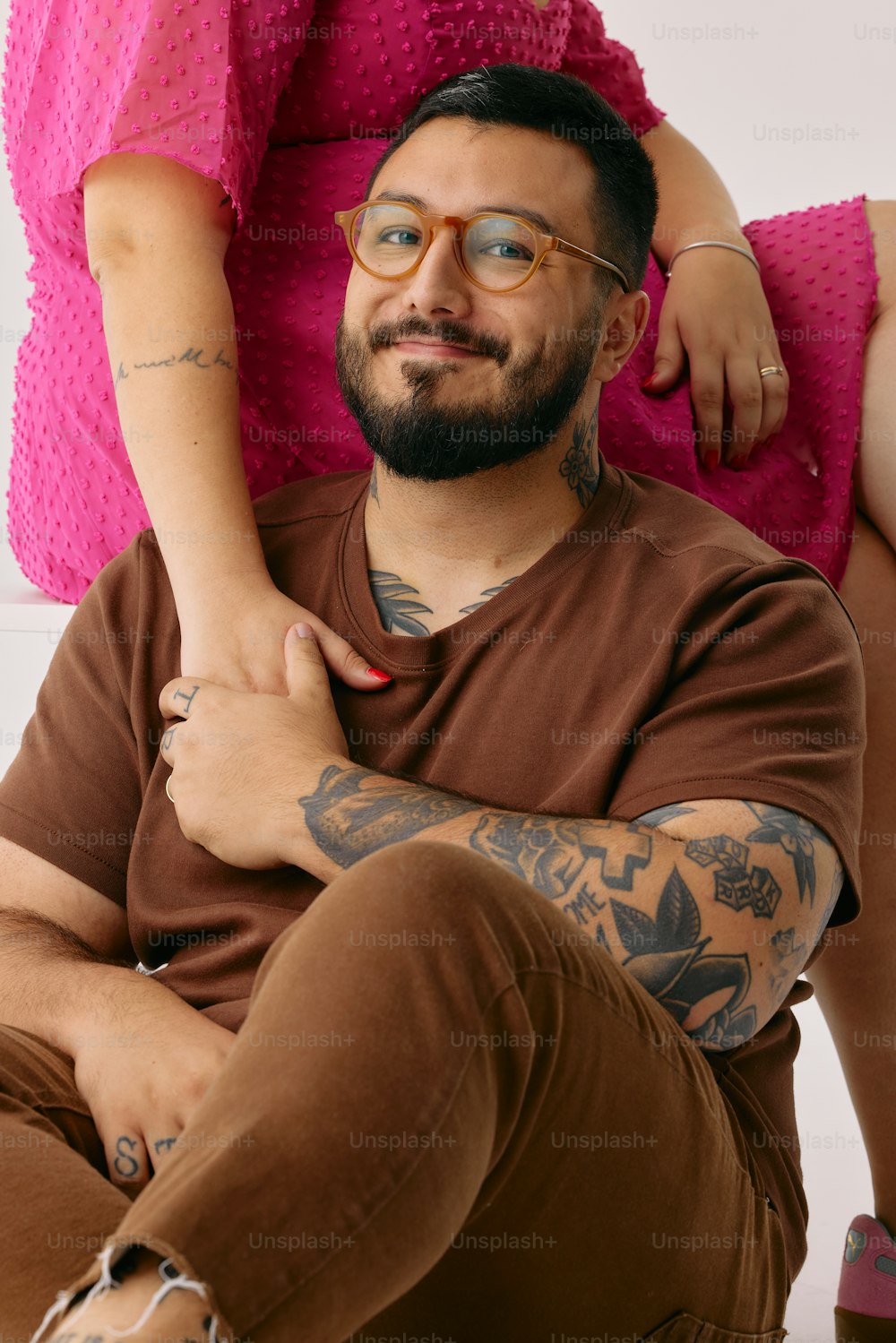 Un hombre con un brazo tatuado sentado en el regazo de una mujer