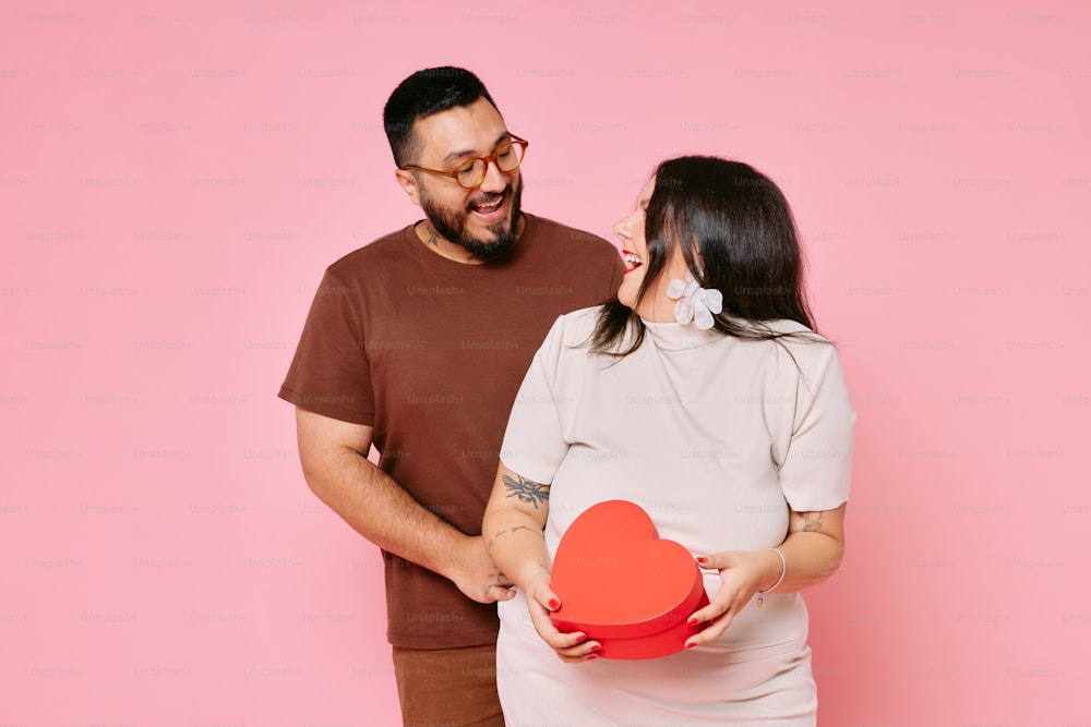 a man holding a heart shaped box next to a woman
