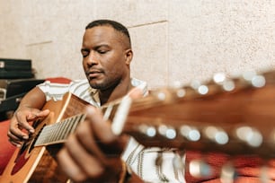 a man sitting on a couch playing a guitar