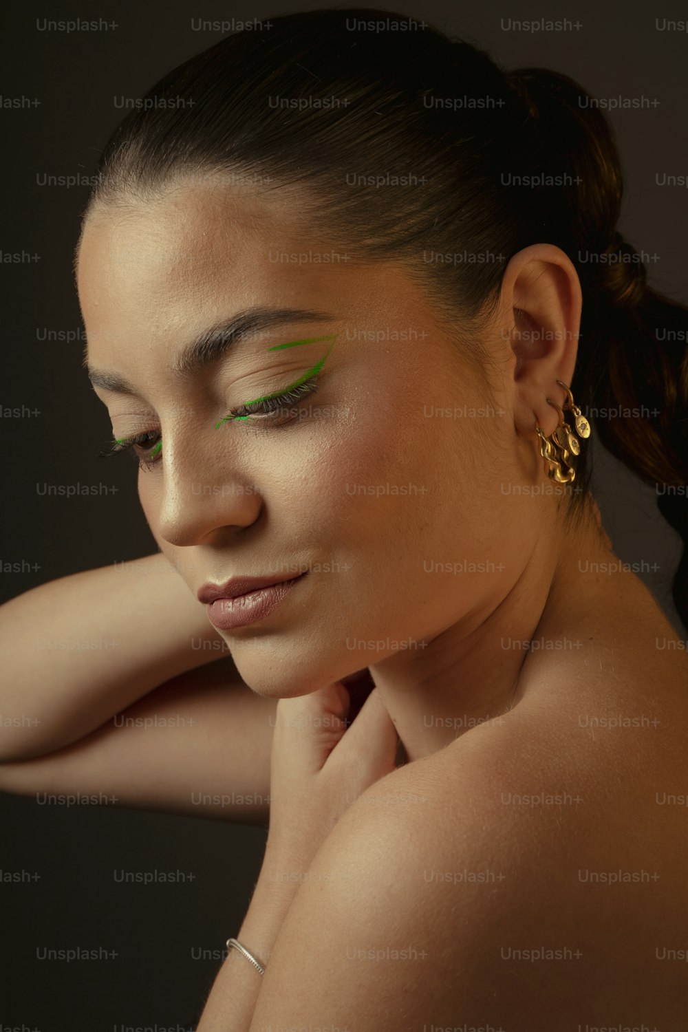 a woman with green eyeshadow and gold earrings