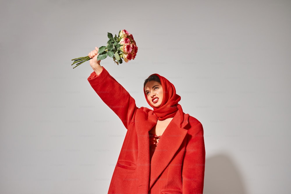 a woman in a red coat holding a bunch of flowers