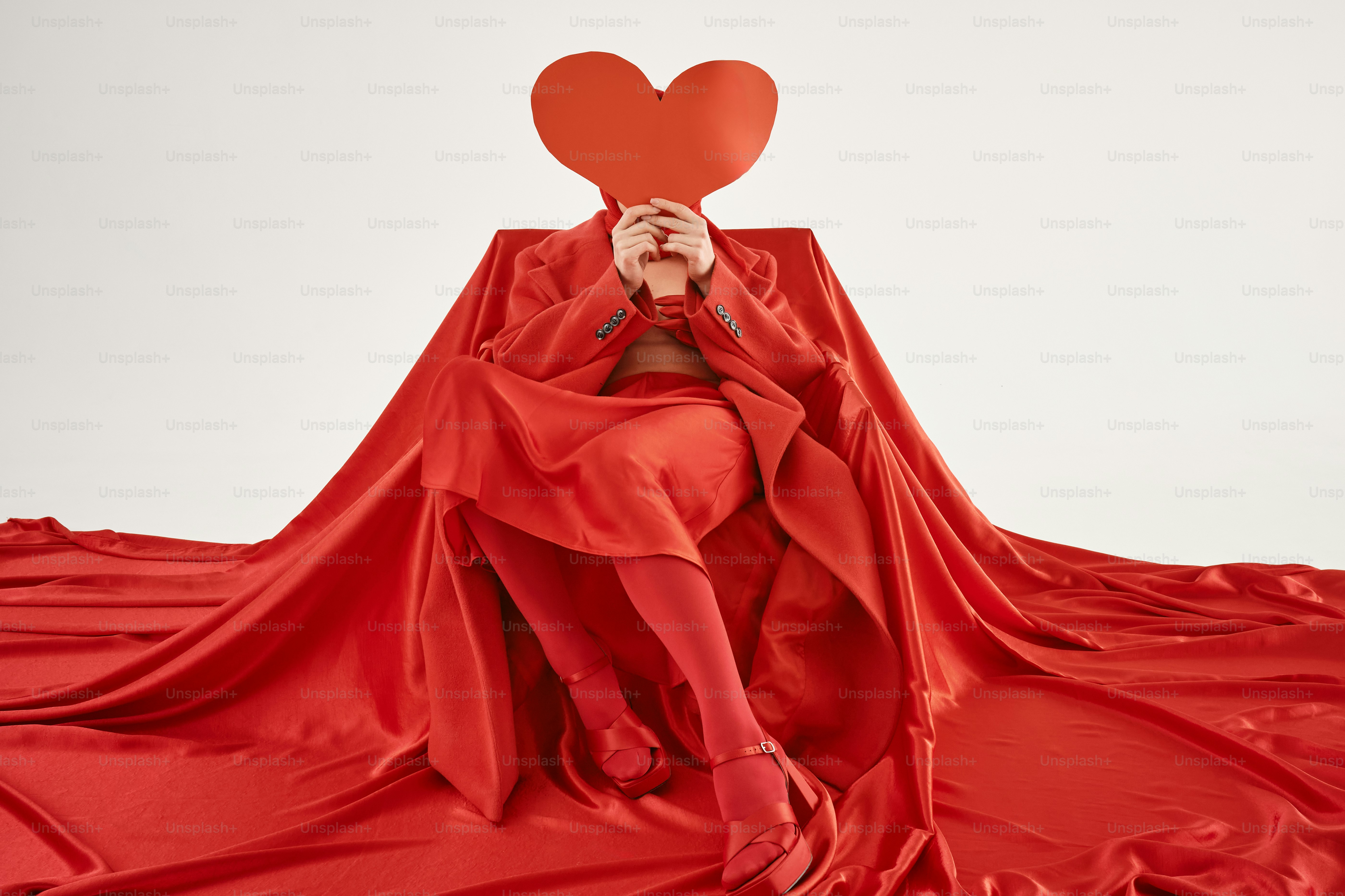 a woman in a red dress holding a red heart over her face