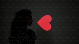 a woman standing in front of a red heart