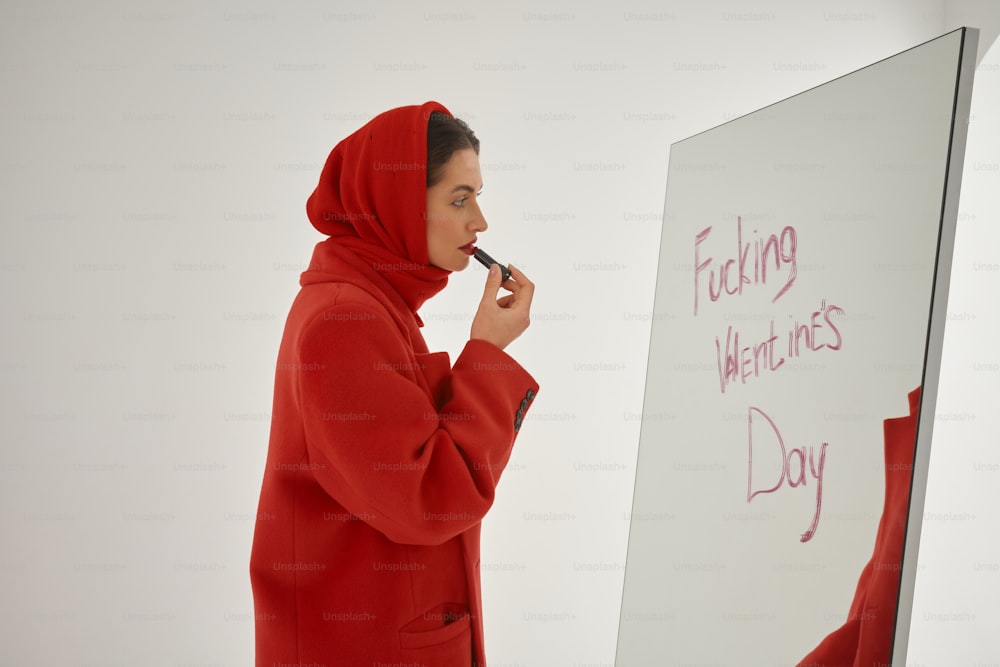 a woman in a red hoodie writing on a white board
