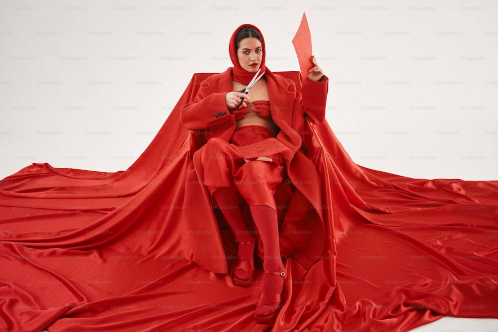 une femme en tenue rouge tenant une paire de ciseaux