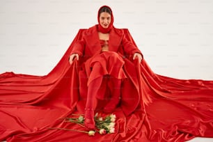 a woman in a red dress sitting on a red sheet