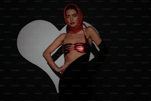 a woman in a bikini top and scarf standing in front of a heart
