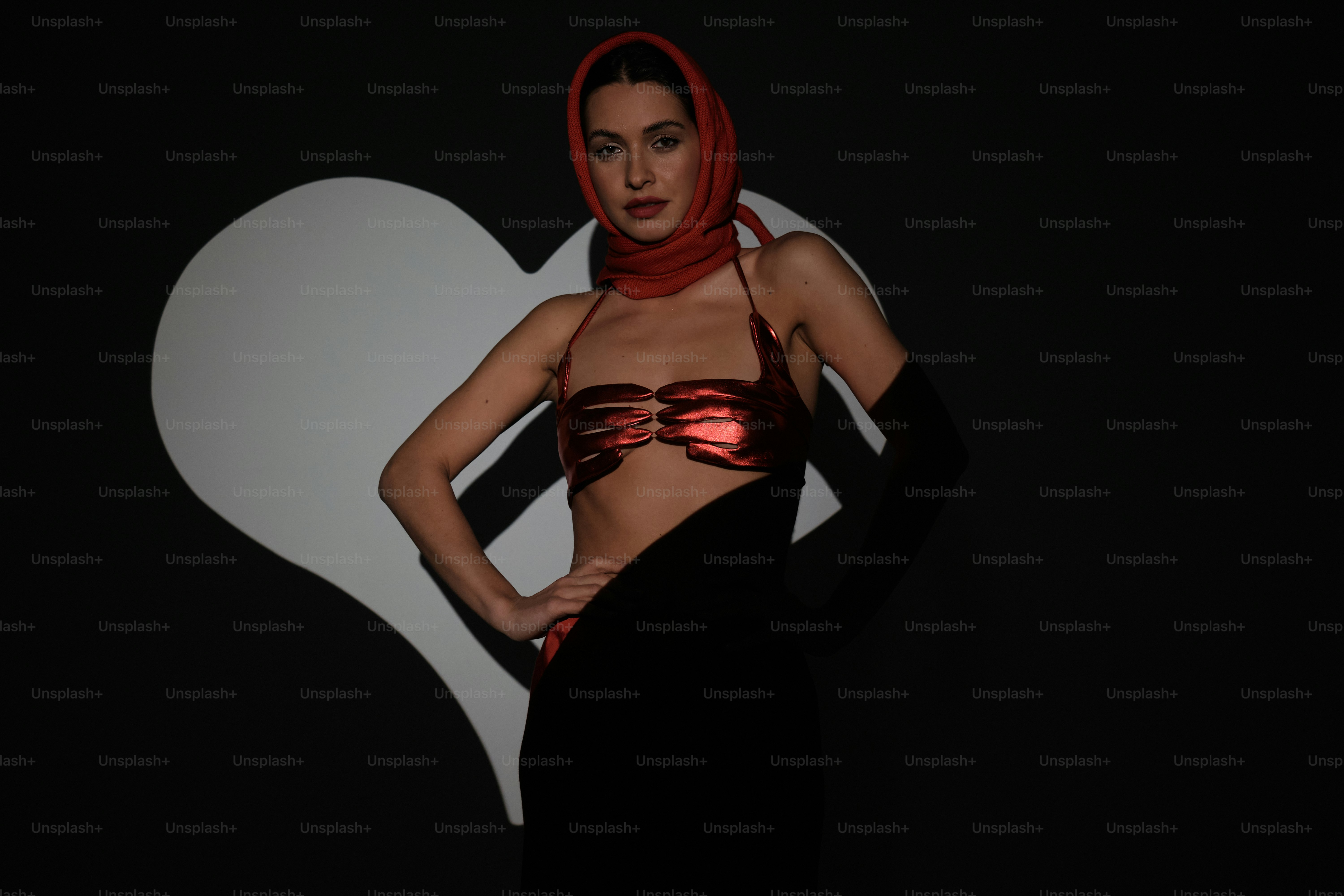 a woman in a bikini top and scarf standing in front of a heart