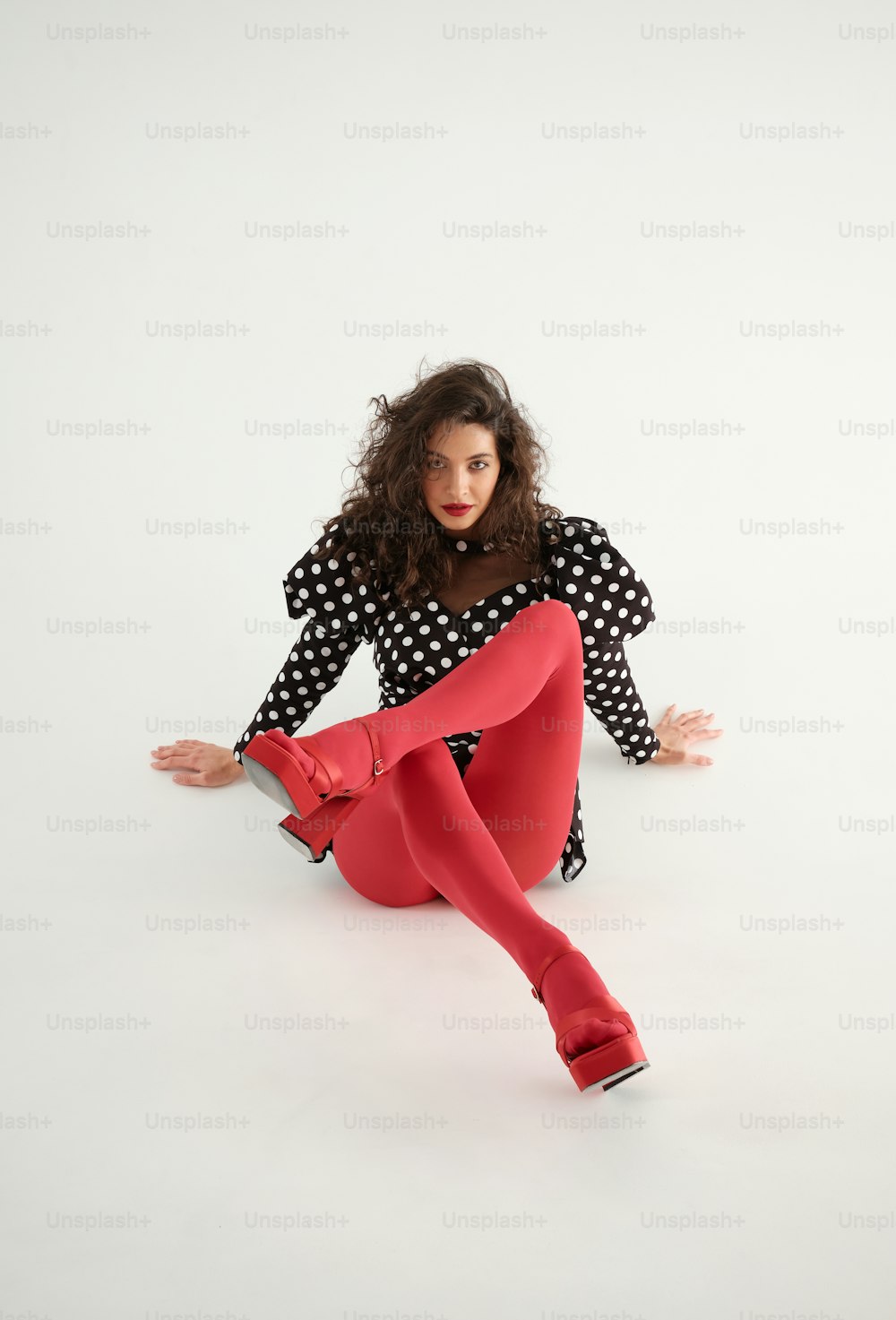 una donna seduta a terra che indossa una calzamaglia rossa