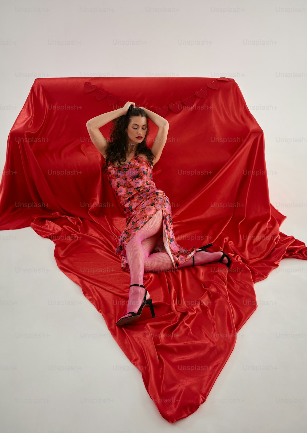 a woman in a red dress laying on a red sheet