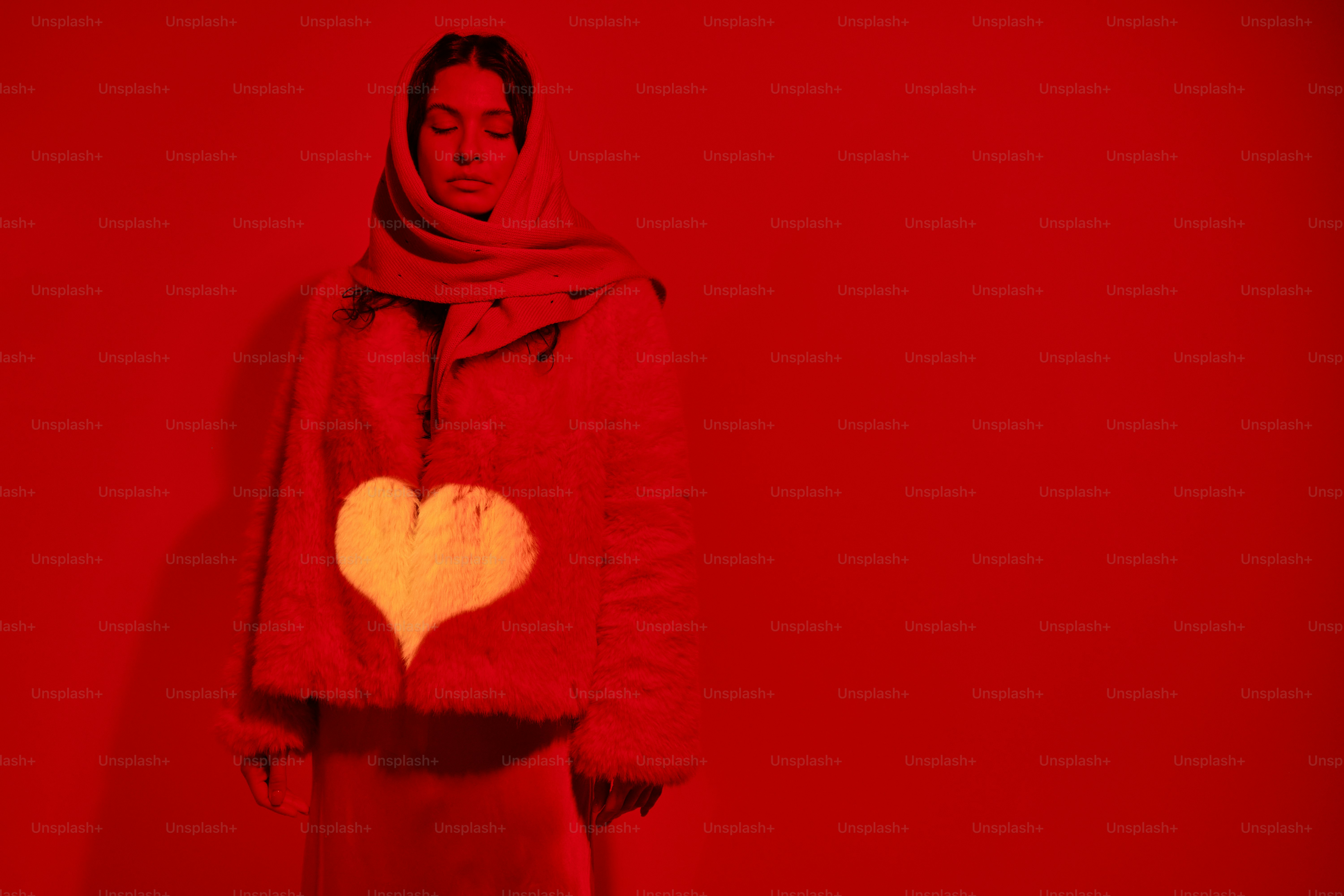 a woman standing in front of a red wall with a heart on it