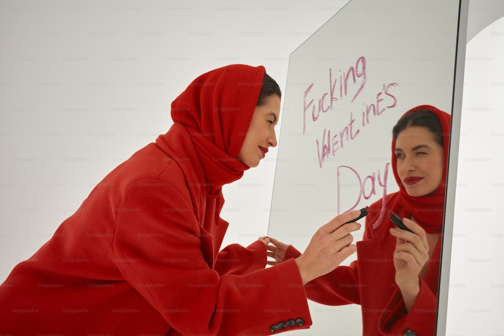 빨간 후드티를 입은 여성이 화이트보드에 글을 쓰고 있다