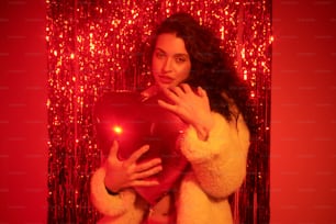 a woman holding a red heart in front of a red background
