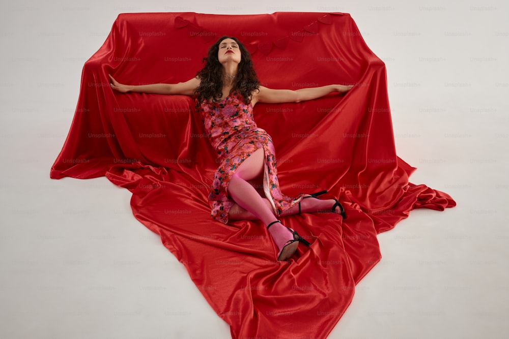 una donna in un vestito rosso sdraiato su un lenzuolo rosso