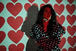 a woman standing in front of a wall with hearts on it
