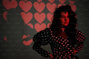 a woman standing in front of a wall with hearts on it