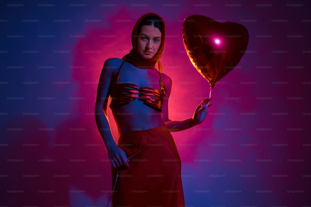 a woman is holding a heart shaped balloon