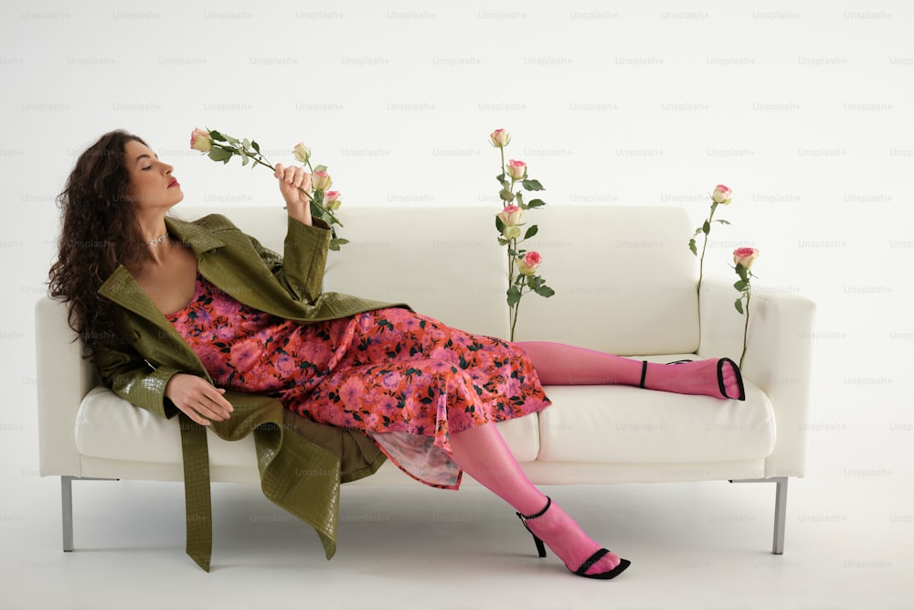 a woman sitting on a couch holding a rose