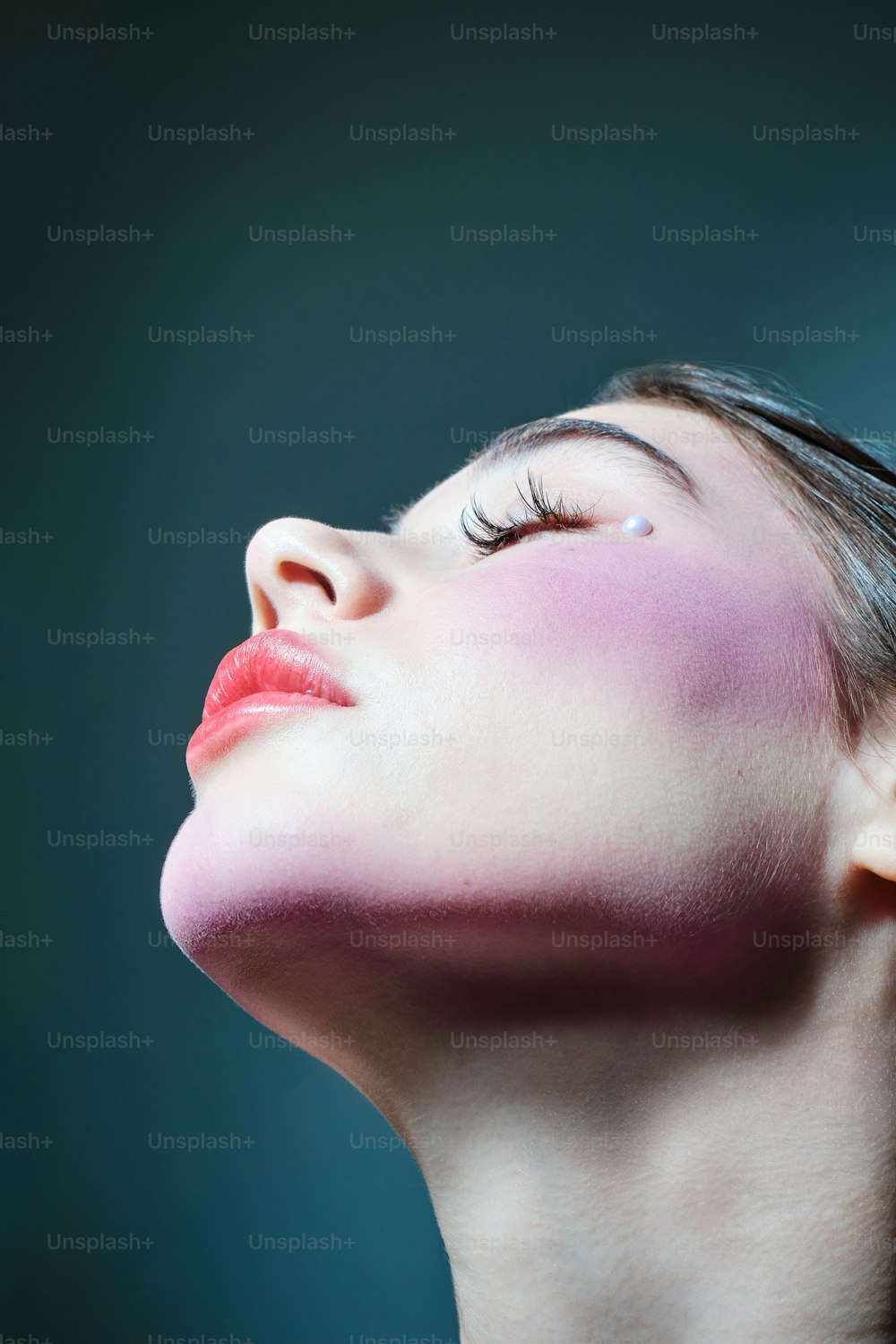eine Frau mit geschlossenen Augen und rosa geschminktem Gesicht
