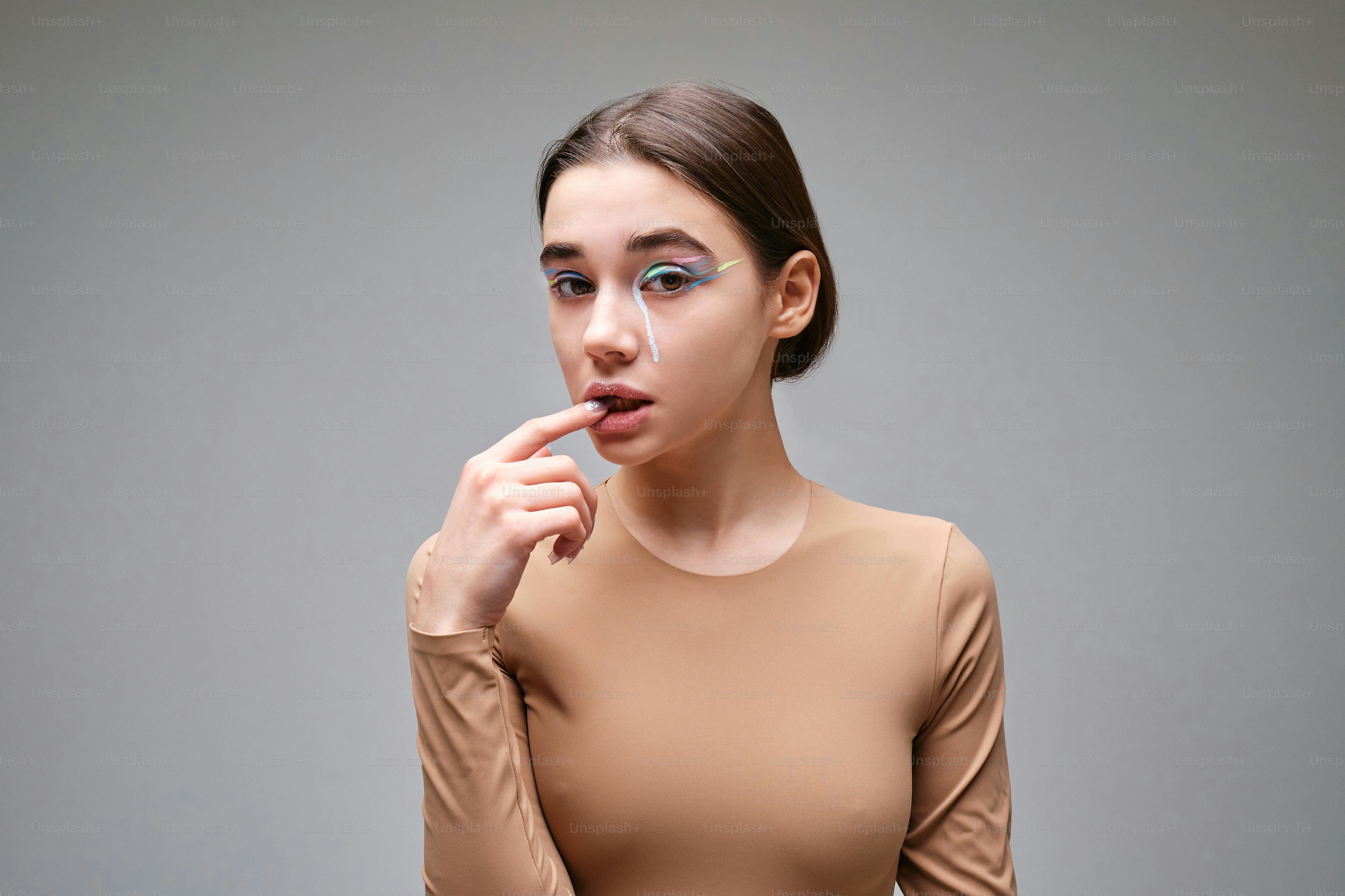 Une femme vêtue d’un haut beige porte son doigt à ses lèvres