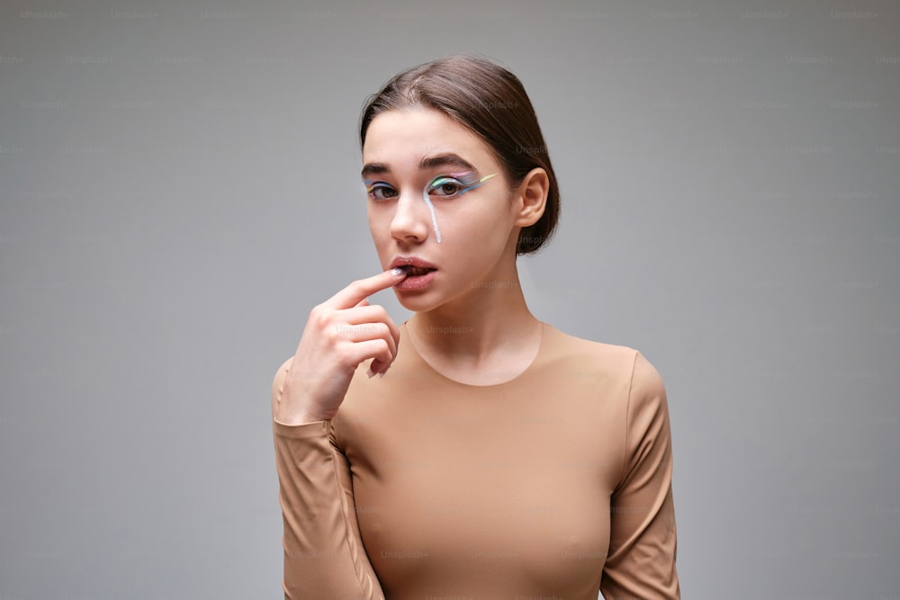 Une femme vêtue d’un haut beige porte son doigt à ses lèvres