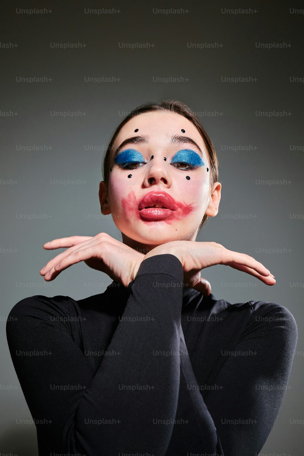 a woman with makeup on her face and hands on her chest