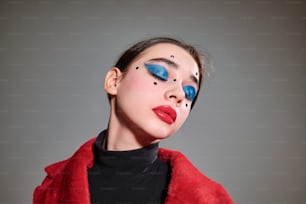 a woman with blue makeup and a red coat