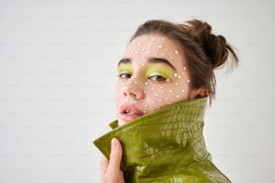 a woman with a green jacket and white dots on her face