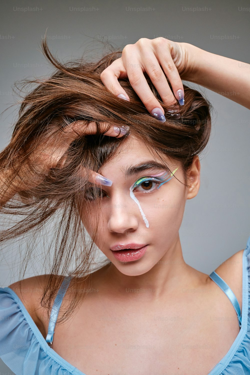 a woman with makeup on her face holding her hair