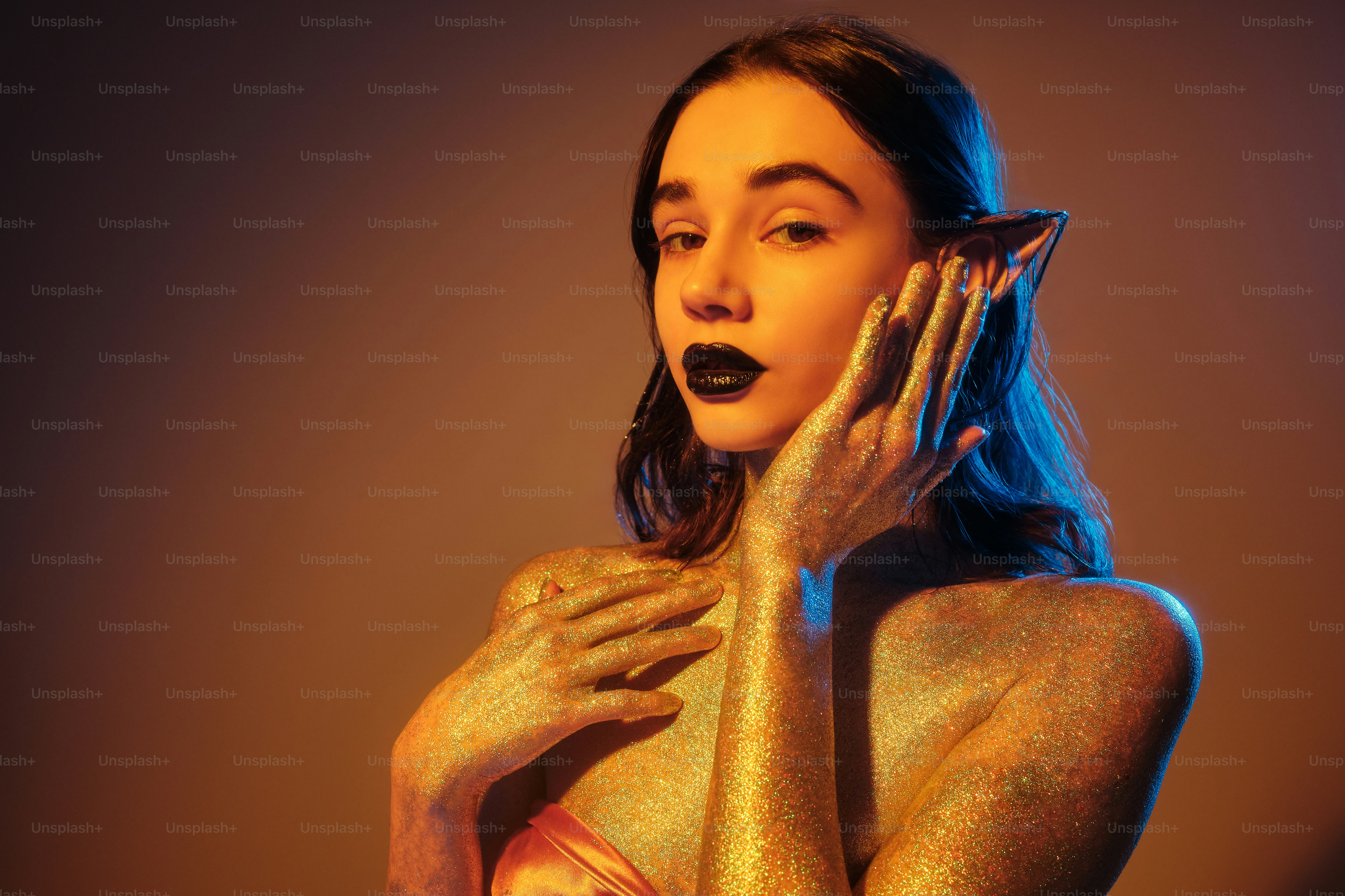 a woman with gold body paint holding her hands up to her face