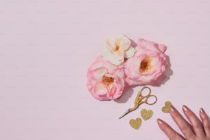 Die Hand einer Person neben einer Schere und Blumen