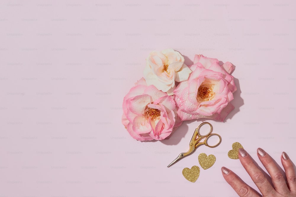 a person's hand next to a pair of scissors and flowers