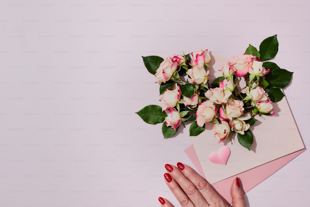la mano de una mujer con esmalte de uñas rojo sosteniendo un ramo de flores