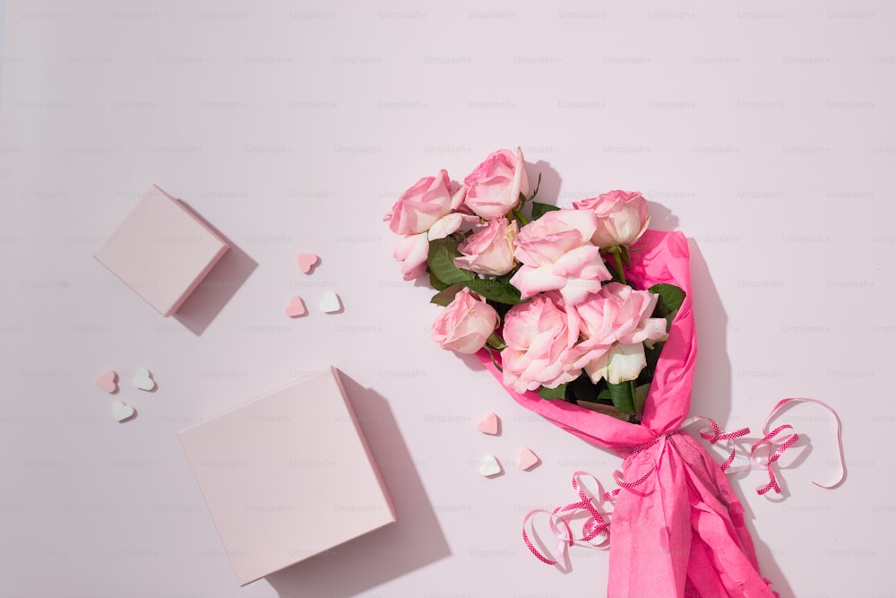 a bouquet of pink roses next to a white box