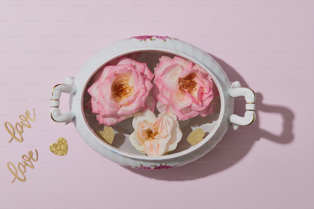 Tre rose rosa sono in una tazza bianca