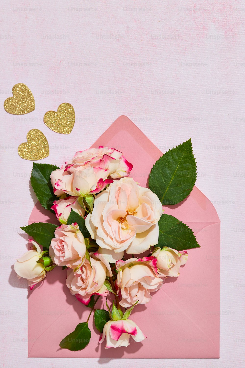 um envelope rosa com um buquê de rosas